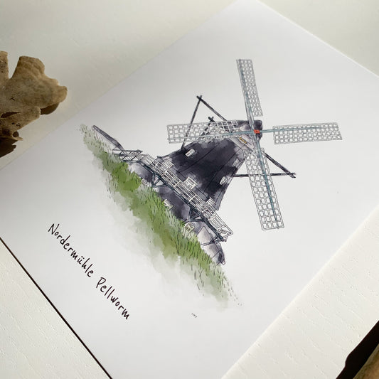 Nahaufnahme einer Postkarte mit schwarzer Windmühle mit weißen Flügeln, darunter der Schriftzug „Nordermühle Pellworm“, auf weißem Papier liegend.