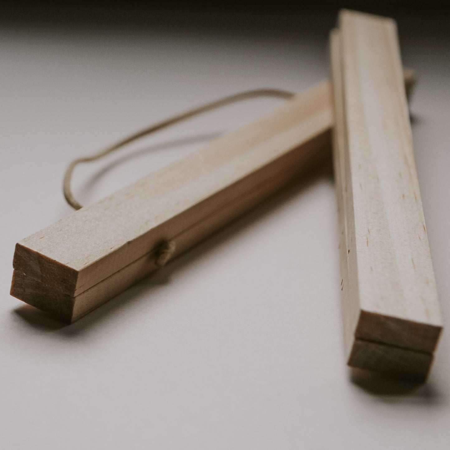 Zwei magnetische Posterleisten aus hellem Holz mit Kordelaufhängung, schräg auf weißem Untergrund liegend.