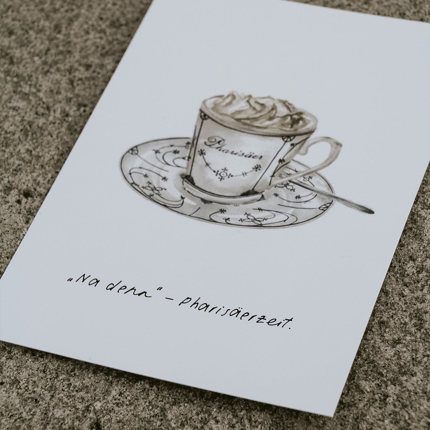 Detailansicht einer Aquarell-Postkarte mit liebevoll gezeichneter Pharisäer-Tasse – dem typischen nordfriesischen Getränk aus Kaffee, Rum und Sahne. Die Karte liegt auf Sand, der Spruch 'Na denn – Pharisäerzeit' ist gut lesbar. Ideal für Liebhaber norddeutscher Kultur.