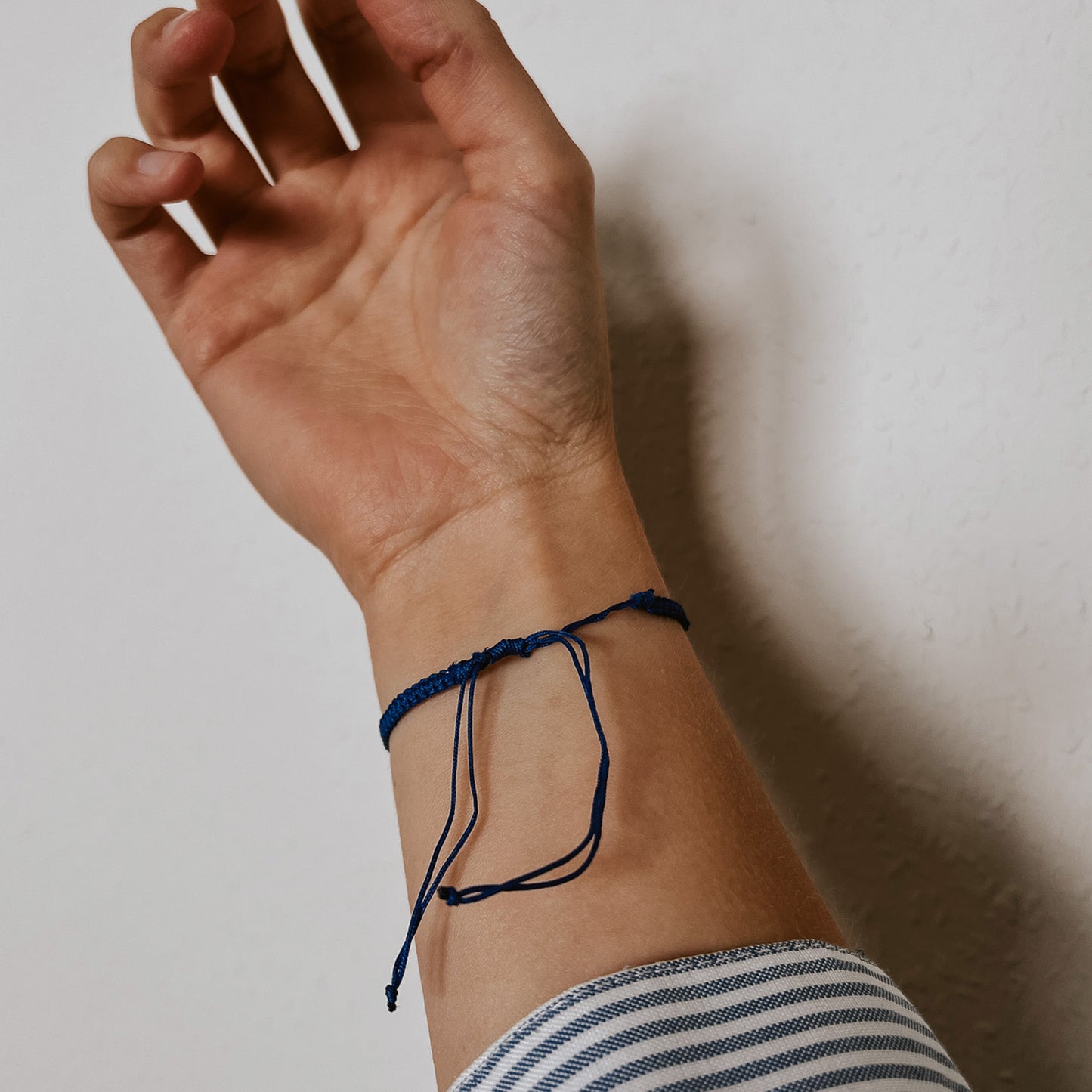 Rückansicht des blauen Bali Armbands mit fein geflochtenem Band und einer weißen Kauri Muschel als Hingucker. Der verstellbare Verschluss ermöglicht eine individuelle Passform und sorgt für einen bequemen Sitz am Handgelenk.