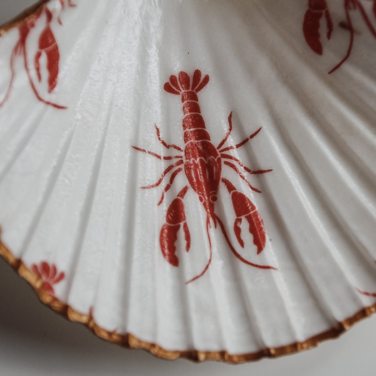 Detailaufnahme der Muschelschale mit rotem Hummer-Print, maritimes Design und goldener Kante von saltwaterdesigns.