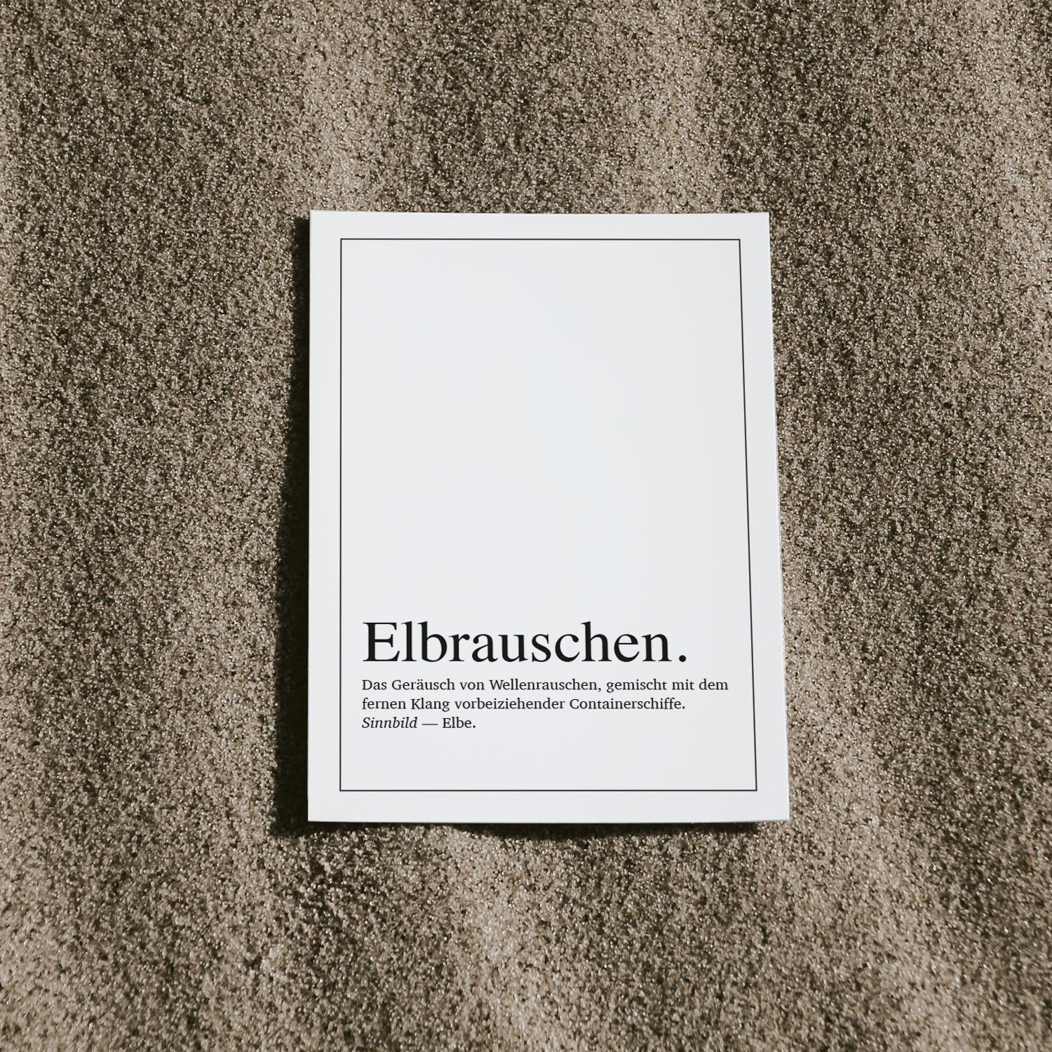 Flatlay einer typografischen Postkarte mit Definition des Begriffs 'Elbrauschen' – inspiriert vom Klang der Elbe, Wellen und Containerschiffen. Klarer, nordisch-maritim gehaltener Look, ideal als stilvolle Grußkarte oder Deko für Liebhaber der Hamburger Küstenatmosphäre.