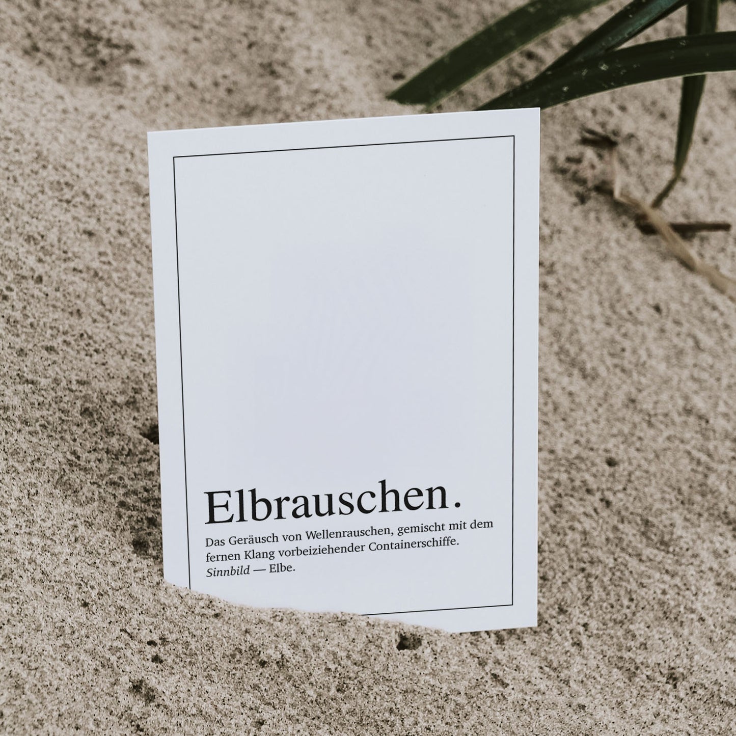 Postkarte 'Elbrauschen Definition' im Duden-Stil, leicht in Sand gesteckt. Typografisches Design mit Bezug zur Elbe, Wellenrauschen und Containerschiffen – ein maritimes Motiv für Hamburg-Fans, ideal als Grußkarte, Geschenk oder Dekoration mit norddeutschem Flair.