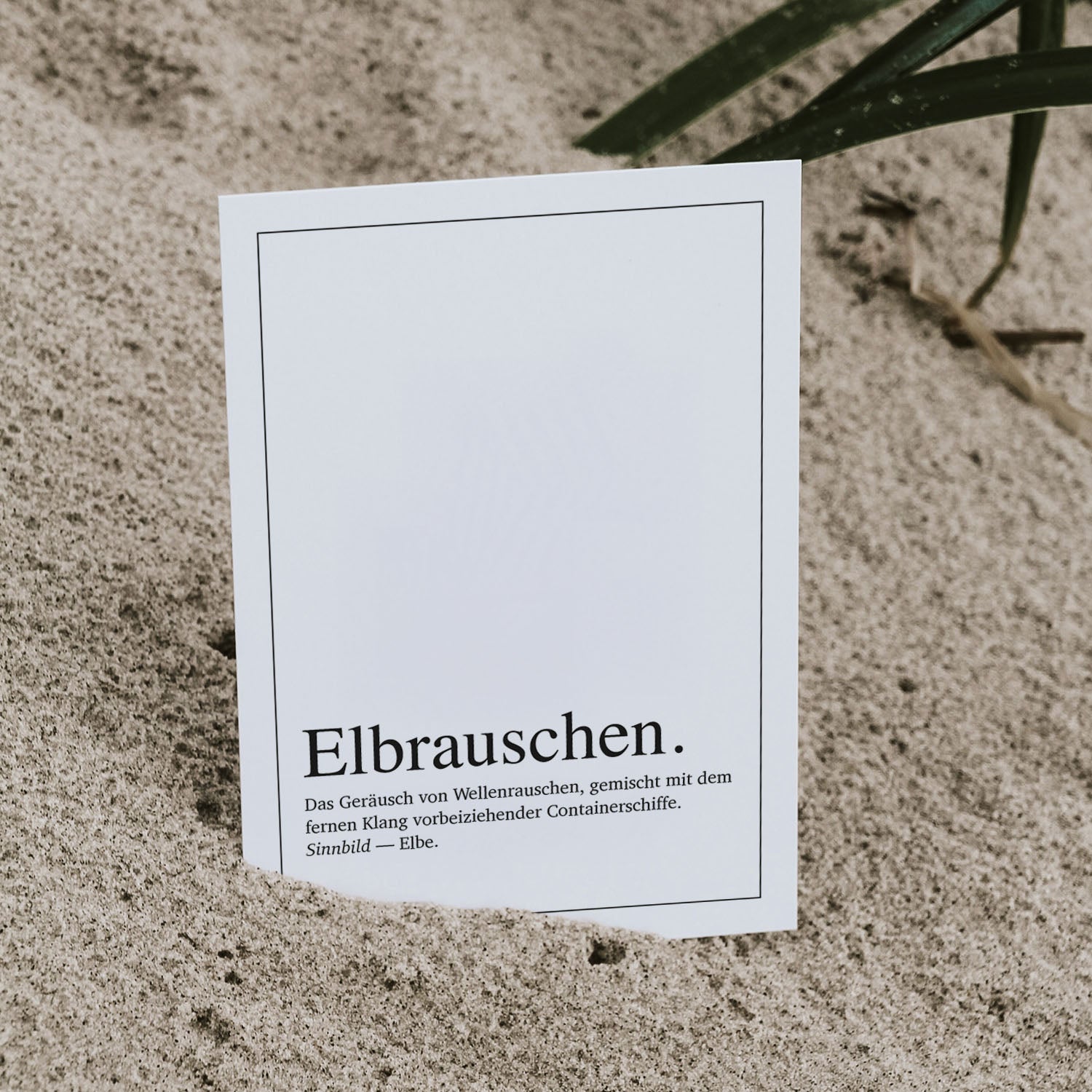 Postkarte 'Elbrauschen Definition' im Duden-Stil, leicht in Sand gesteckt. Typografisches Design mit Bezug zur Elbe, Wellenrauschen und Containerschiffen – ein maritimes Motiv für Hamburg-Fans, ideal als Grußkarte, Geschenk oder Dekoration mit norddeutschem Flair.