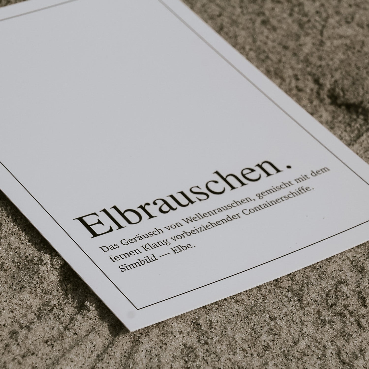 Detailansicht der Postkarte 'Elbrauschen Definition' mit typografischem Design im Duden-Stil. Die feine Schrift und klare Gestaltung fangen das maritime Gefühl der Elbe ein – ideal als stilvolle Grußkarte oder Dekoration für Liebhaber norddeutscher Küstenmomente.