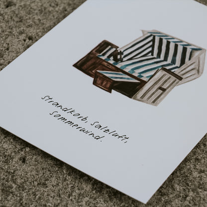 Detailaufnahme von der illustrierten Postkarte im maritimen Stil mit Strandkorb-Motiv und dem Schriftzug „Strandkorb, Salzluft, Sommerwind“. Direkt am Nordseestrand eingefangen – ideal als sommerliches Wohnaccessoire, liebevolles Geschenk oder Urlaubsgruß. Erhältlich bei Saltwaterdesigns.