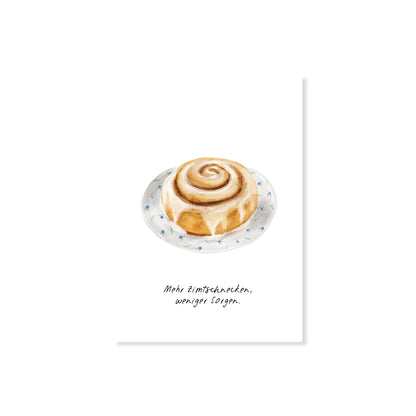 Postkarte Zimtschnecke mit Spruch 'Mehr Zimtschnecken, weniger Sorgen', Nahaufnahme auf weißem Hintergrund.