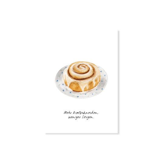 Postkarte Zimtschnecke mit Spruch 'Mehr Zimtschnecken, weniger Sorgen', Nahaufnahme auf weißem Hintergrund.