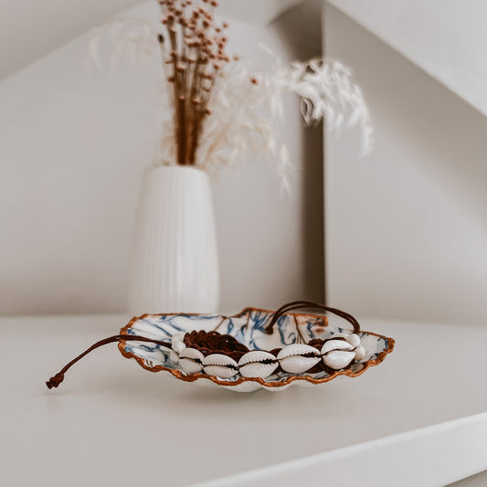 Kauri Muschelarmband präsentiert auf einer Schmuckschale von saltwaterdesigns namens Muschelschale Muriwai. Auf weißem Schrank, im Hintergrund Blumen und zeigt allgmein ein Deko-Beispiel.