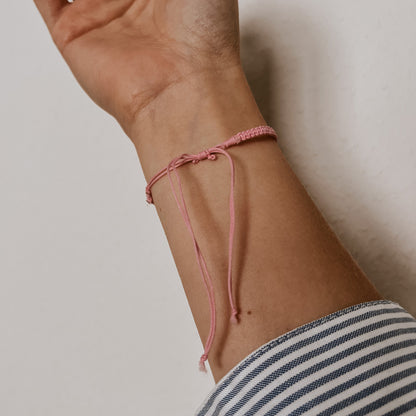 Rückansicht des rosa Bali Armbands mit rosa Band und weißer Kauri Muschel. Der Verschluss ist individuell verstellbar.