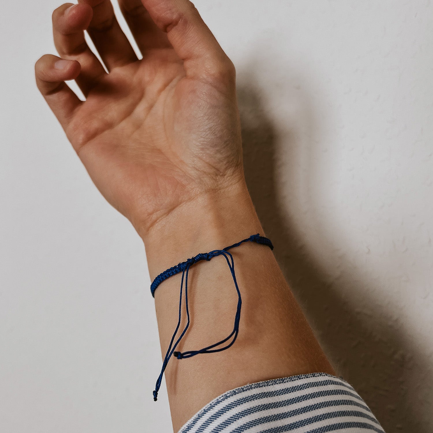 Rückansicht des blauen Bali Armbands mit fein geflochtenem Band und einer weißen Kauri Muschel als Hingucker. Der verstellbare Verschluss ermöglicht eine individuelle Passform und sorgt für einen bequemen Sitz am Handgelenk.