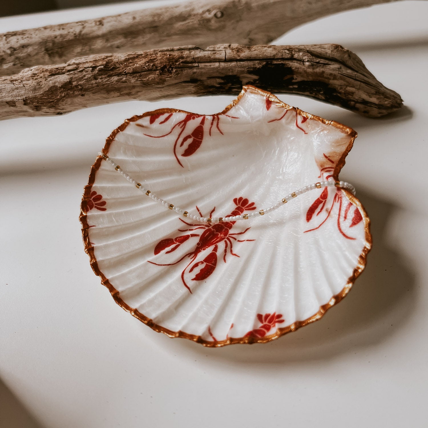 Pearl Armband in blau platziert auf der Lobster Muschelschale mit Goldrand. Ein echter Hingucker in jedem Zimmer.