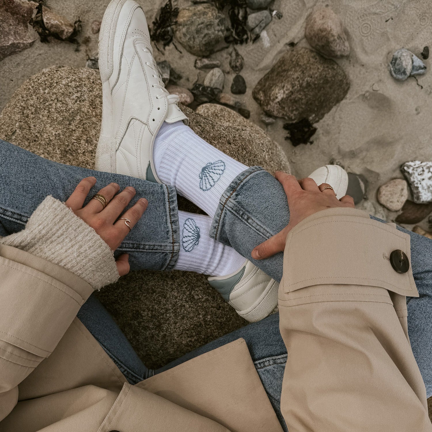 Detail-Aufnahme Saltwater Tennissocken Socken mit Jakobsmuschel-Motiv, kombiniert mit Ringen und Jeans auf Granitstein.