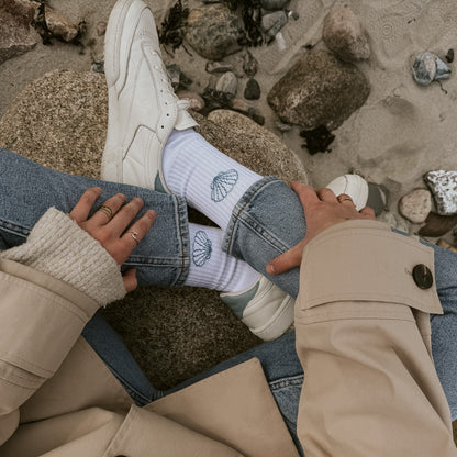 Detail-Aufnahme Saltwater Tennissocken Socken mit Jakobsmuschel-Motiv, kombiniert mit Ringen und Jeans auf Granitstein.